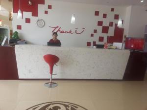 a woman sitting at a counter in a restaurant with a red stool at Thank Inn Chain Hotel Jiangsu Wuxi New District Taibo Avenue in Wuxi