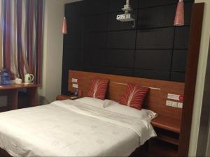 1 dormitorio con 1 cama con sábanas blancas y almohadas rojas en Thank Inn Chain Hotel Shangxi Changzhi Daqing Road, en Changzhi