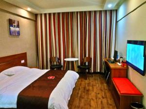 Habitación de hotel con cama, escritorio y TV. en Thank Inn Chain Hotel Hubin District Dongfeng Market, en Sanmenxia