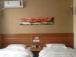 a bedroom with two beds and a painting on the wall at Thank Inn Chain Hotel Hebei Langfang the 6th Street in Langfang