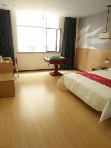 een slaapkamer met een bed, een tafel en een raam bij Thank Inn Shanxi Shuozhouying County West Jingcheng Street in Ying