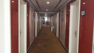 an empty hallway with red and white walls and a long corridor at Thank Inn Chain Hotel Hebei Cangzhou Qing County Jingfu Avenue in Qing