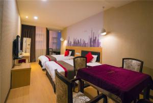 a hotel room with three beds and a table and chairs at Thank Inn Chain Hotel Sichuan Guangan Wusheng County Hongwu Avenue in Wusheng