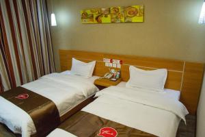 two beds in a hotel room with a phone at Thank Inn Chain Hotel Gansu Jinchang Heya Road in Pai-chia-tsui