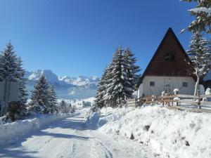 a snow covered road in front of a barn at Apartment Andjela in Žabljak