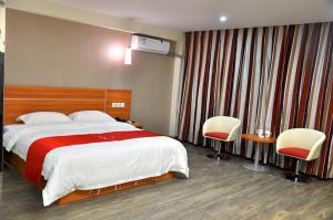 ein Hotelzimmer mit einem großen Bett und zwei Stühlen in der Unterkunft Thank Inn Chain Hotel Henan Xinyang Shangcheng County Huayuan Road in Shangcheng