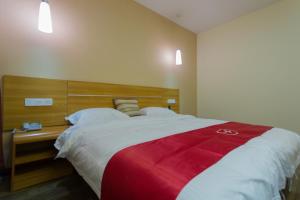 Schlafzimmer mit einem großen Bett mit einem Kopfteil aus Holz in der Unterkunft Thank Inn Plus Hotel Henan Luoyan Xigong District Wangcheng Avenue in Luoyang