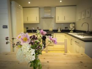 Castle View في لانكستر: مزهرية مليئة بالورود على طاولة في مطبخ
