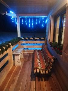 eine Veranda mit Bänken und Lichtern auf einer Terrasse in der Unterkunft Młynarzowa Chata in Lesko
