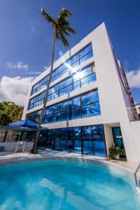 um edifício com piscina em frente a uma palmeira em VOA Ambassador Flat em João Pessoa