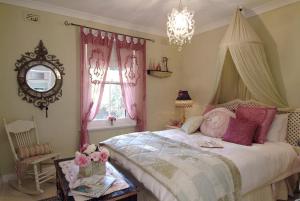 1 dormitorio con 1 cama con cortinas rosas y lámpara de araña en Jasmine's Barossa Valley Cottage en Lyndoch
