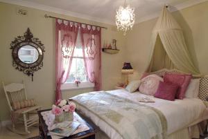 a bedroom with a bed with pink curtains and a chandelier at Jasmine's Barossa Valley Cottage in Lyndoch