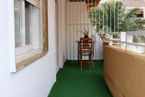 a balcony with green flooring and a chair and a window at Apartamento a 5 min de la playa y el centro in Almería
