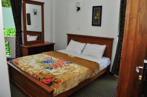 1 dormitorio con 1 cama con manta de flores en Coolborn Apartment, en Nuwara Eliya