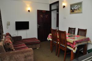 una sala de estar con una mesa y un sofá en Coolborn Apartment, en Nuwara Eliya