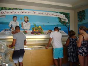 a group of people standing around a counter in a kitchen at Rhodian Rose Hotel in Faliraki