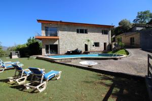 a house with lawn chairs and a swimming pool at Casa de Paredes Secas by Gerês Casas in Amares