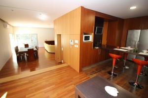 a kitchen with wooden cabinets and a living room at Casa de Paredes Secas by Gerês Casas in Amares