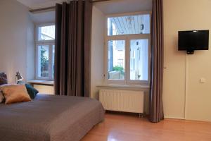 1 Schlafzimmer mit einem Bett, 2 Fenstern und einem TV in der Unterkunft Mini Home Vilnius Old Town in Vilnius