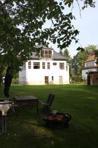 a large white house with a table and a fire pit at Haus Seeblick Bestensee in Bestensee