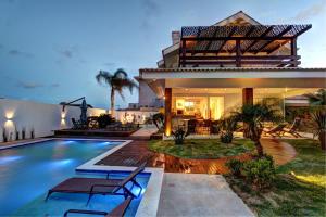 a villa with a swimming pool in front of a house at Casa do Artista a 60m do mar, piscina, 4 quartos in Bombinhas