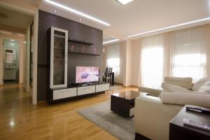 ein Wohnzimmer mit einem weißen Sofa und einem TV in der Unterkunft Belville Superior in Belgrad