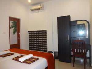 1 dormitorio con cama, escritorio y espejo en i - One's Home Stay, en Kochi