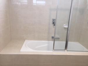 a shower with a glass door next to a tub at B2 Brand new home in Mitcham