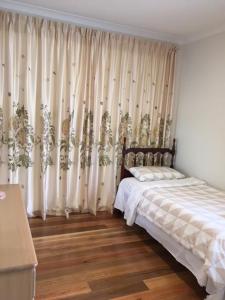 um quarto com uma cama com cortinas e pisos em madeira em B2 Brand new home em Mitcham