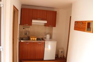 a small kitchen with wooden cabinets and a white refrigerator at Mikulin Apartments in Lumbarda
