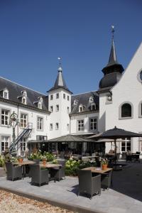 dziedziniec ze stołami, krzesłami i budynkami w obiekcie Hotel Kasteel Doenrade w mieście Doenrade