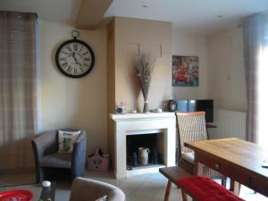 a living room with a fireplace and a clock on the wall at Chez Fanou in Yport