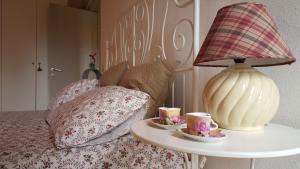 a bed with a table with two cups and a lamp at Casa Di Arianna in Ferrara