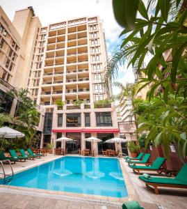 un grand hôtel avec une piscine, des chaises et un bâtiment dans l'établissement Le Commodore Hotel, à Beyrouth