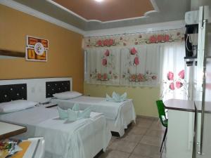 Zimmer mit 2 Betten und einem Fenster mit Blumen in der Unterkunft Varanda Hotel in Arapiraca