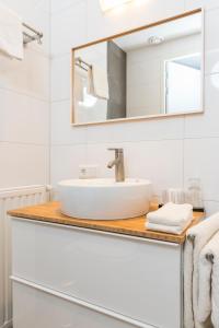 a bathroom with a sink, mirror, and bathtub at Hotel Bosch En Zee in Domburg