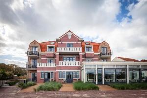 a large pink building with a lot of windows at Hotel Bosch En Zee in Domburg