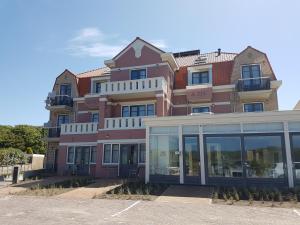 a tall pink building with a lot of windows at Hotel Bosch En Zee in Domburg
