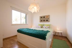 a bedroom with a bed with a green blanket at Exciting Beach Apartment in Charneca