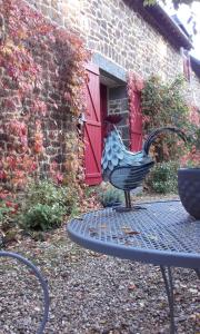 una estatua de un pollo en una mesa frente a un edificio en Le Domaine, en Les Iffs