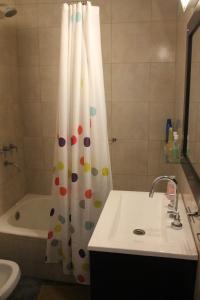 a bathroom with a shower curtain with a sink and a tub at Petit Maipu in Buenos Aires