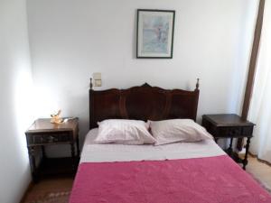 1 dormitorio con 1 cama con manta rosa y 2 mesas en Rustico & Singelo - Hotelaria e Restauração, Lda, en Vila Real