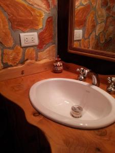 ein Badezimmer mit einem weißen Waschbecken und einem Spiegel in der Unterkunft Cabañas Vientos del Sur in Villa Yacanto