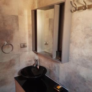 uma casa de banho com um lavatório preto e um espelho em Vicuña Lodge em San Pedro de Atacama