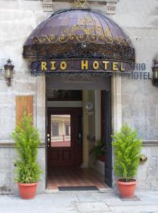 a hotel with two potted plants in front of a door at Rio Hotel in Riobamba