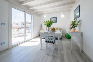 una sala da pranzo bianca con tavolo e sedie bianchi di Deliziosi Appartamenti Sul Mare a Leuca