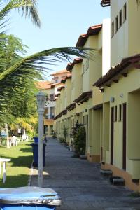 una acera con una fila de edificios y una palmera en Apart Hotel Marinas do Canal, en Cabo Frío