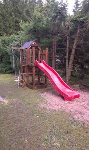 a playground with a red slide and a swing at Chata Vysočina in Svratouch