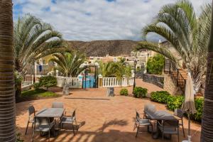 een patio met tafels en stoelen en palmbomen bij Luxe Appartement Palm Mar in Palm-mar