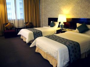 una habitación de hotel con 3 camas y una lámpara en Hotel Royal, en Singapur
